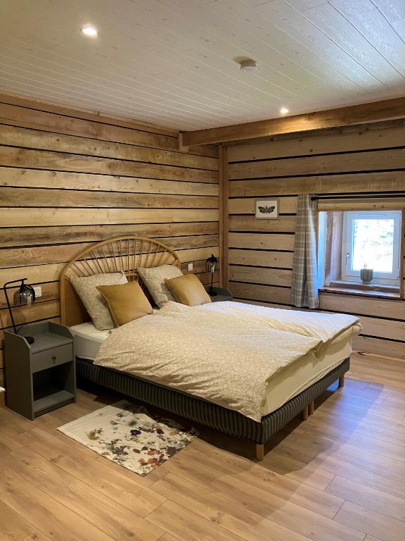 a bedroom with a bed with wooden walls and a window at Le printemps, gîte nature in Bruyères
