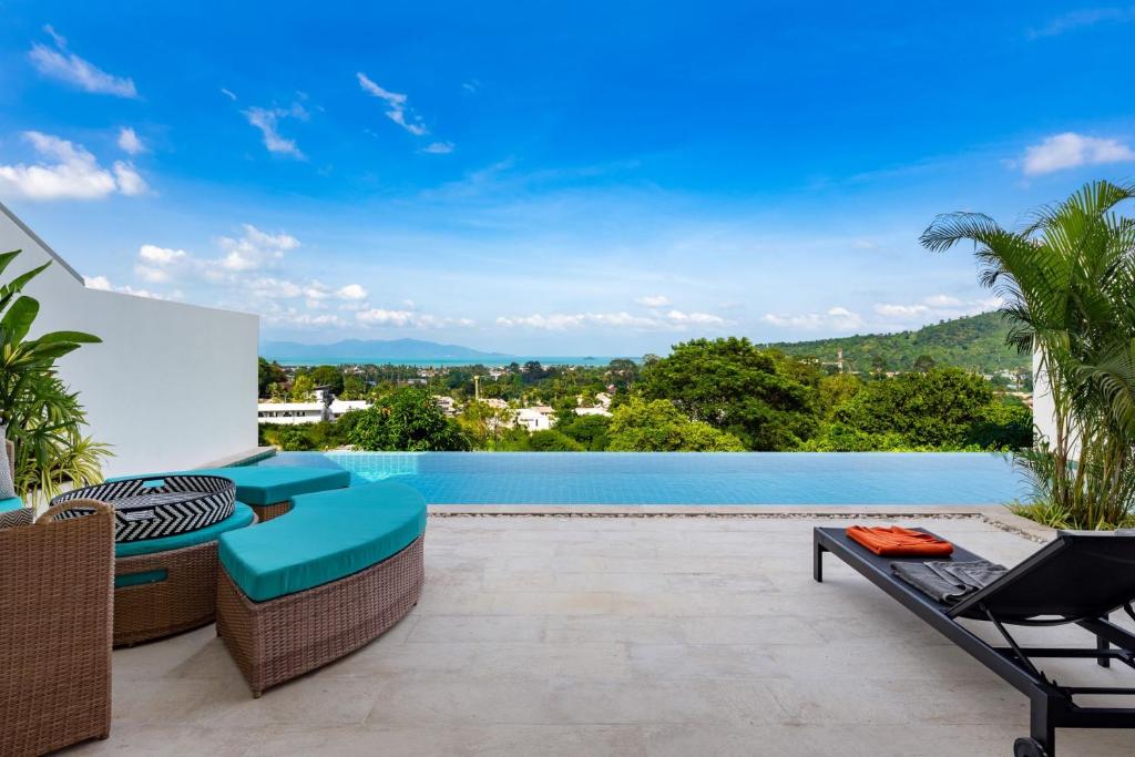 an outdoor patio with chairs and a swimming pool at Stunning X Space Villa Sea View Infinity Pool in Koh Samui