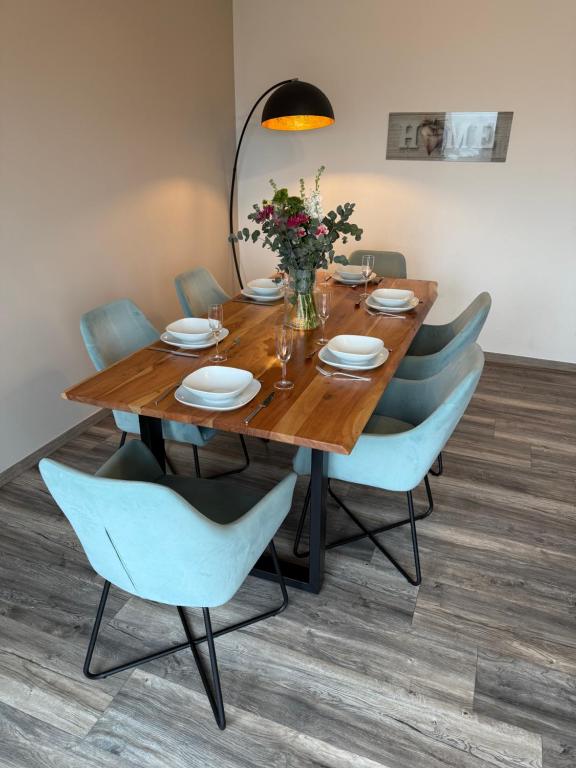 a wooden table with blue chairs and a dining room at Moderne Wohnung mit Parkplatz und Kaffeevollautomat in Zülpich