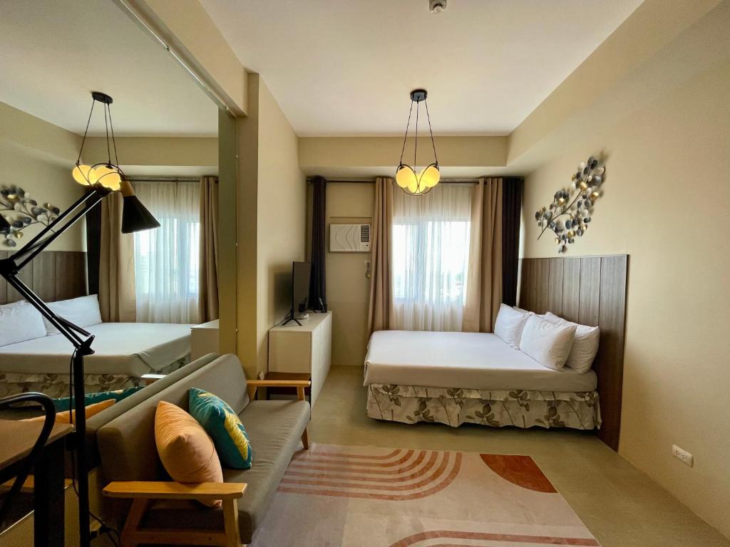 a hotel room with two beds and a couch at A city escape at the Avida Towers Aspira 1 in Cagayan de Oro
