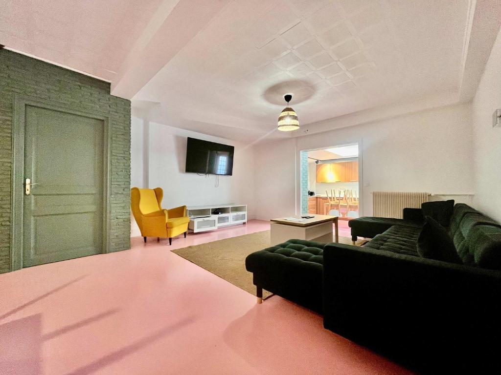 a living room with a black couch and a yellow chair at Grande Maison 17 personnes in Arras
