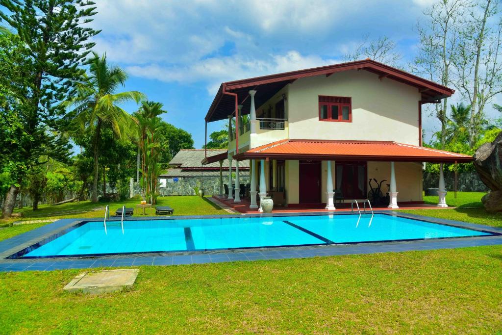 a villa with a swimming pool in front of a house at Niko Villa in Kosgoda