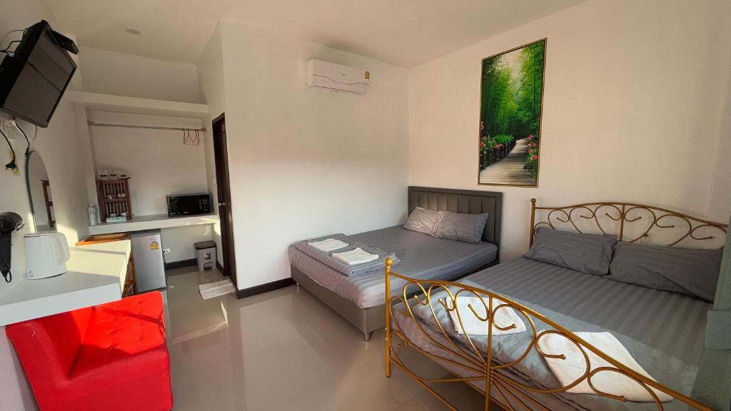 a small room with two beds and a tv at Malee Guesthouse in Ban Rak Thai