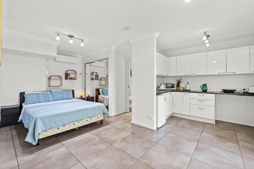 a large white bedroom with a bed and a kitchen at One bedroom studio in North Tamborine
