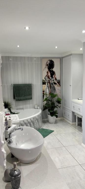 a bathroom with a tub and a sink and a bath tub at Le Clus Stay in Bloemfontein
