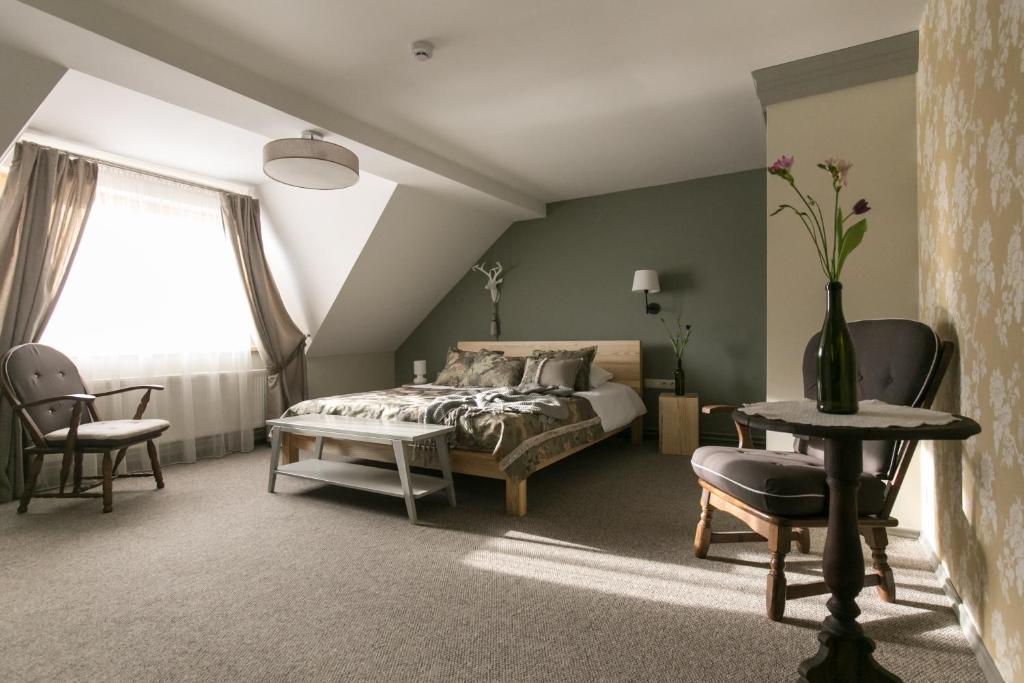 1 dormitorio con 1 cama, mesa y sillas en Guest House Mazais Ansis, en Rubene