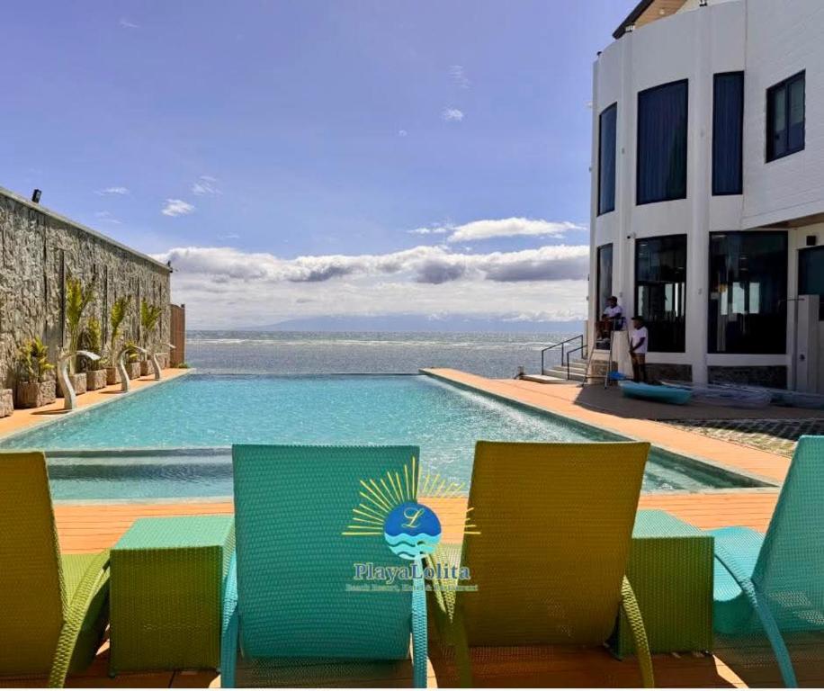 a swimming pool with green chairs and a swimming pool at PlayaLolita Beach Resort in Calatagan