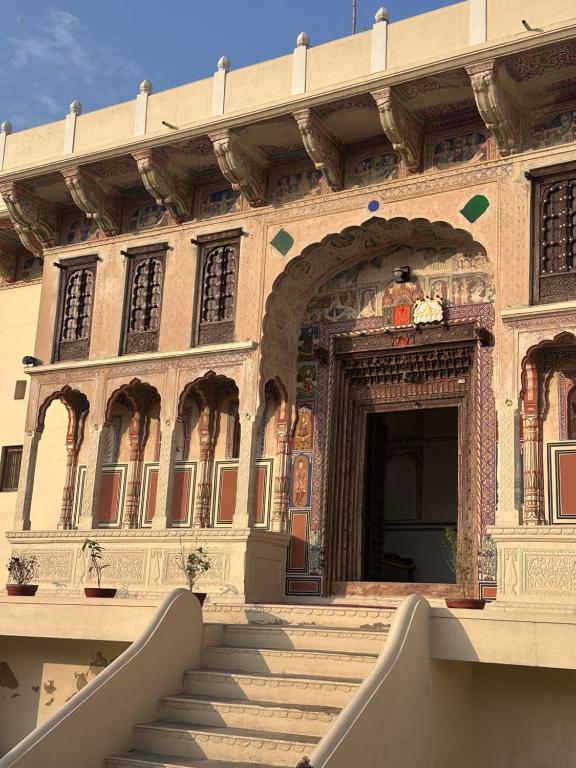 a building with stairs leading to a large doorway at Haveli Kesar Vilas in Chāran ki Dhāni