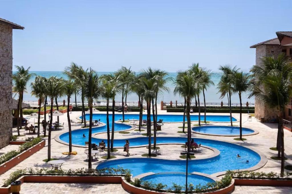 a view of a resort pool with palm trees at Beach Front Apartment Kariri in Caucaia