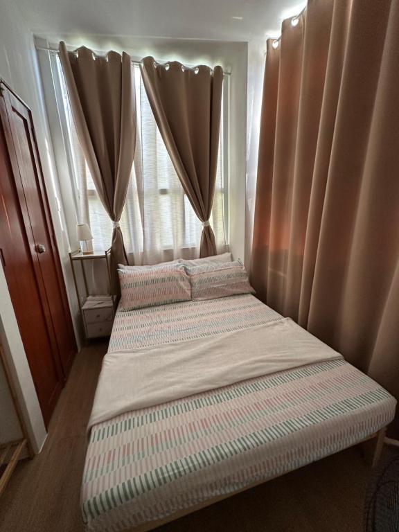 a small bed in a room with curtains at Bayanihan Flats 2 in Mactan