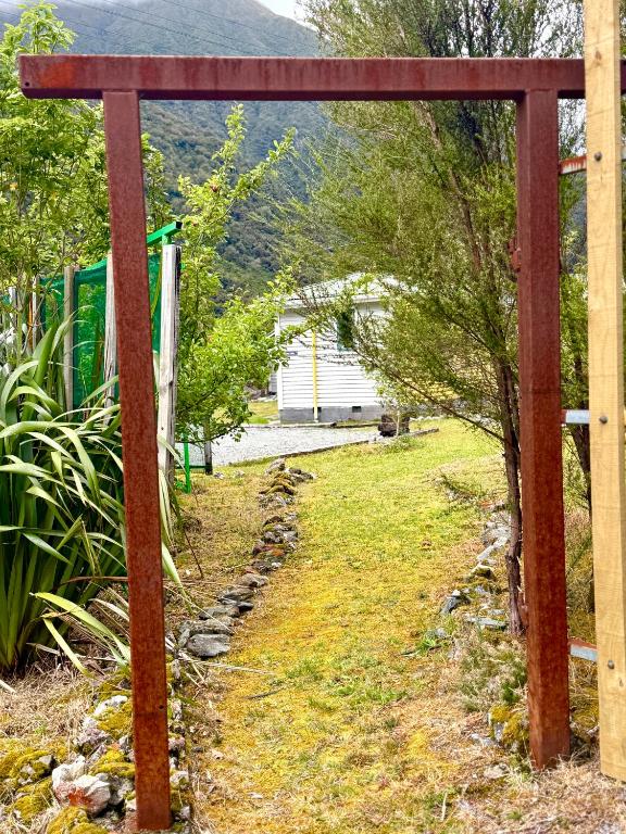 a wooden archway in a yard with trees at Super 'Cosy' Small Basic Cabin in The Middle of National Park and Mountains but near Road and Railway in Otira