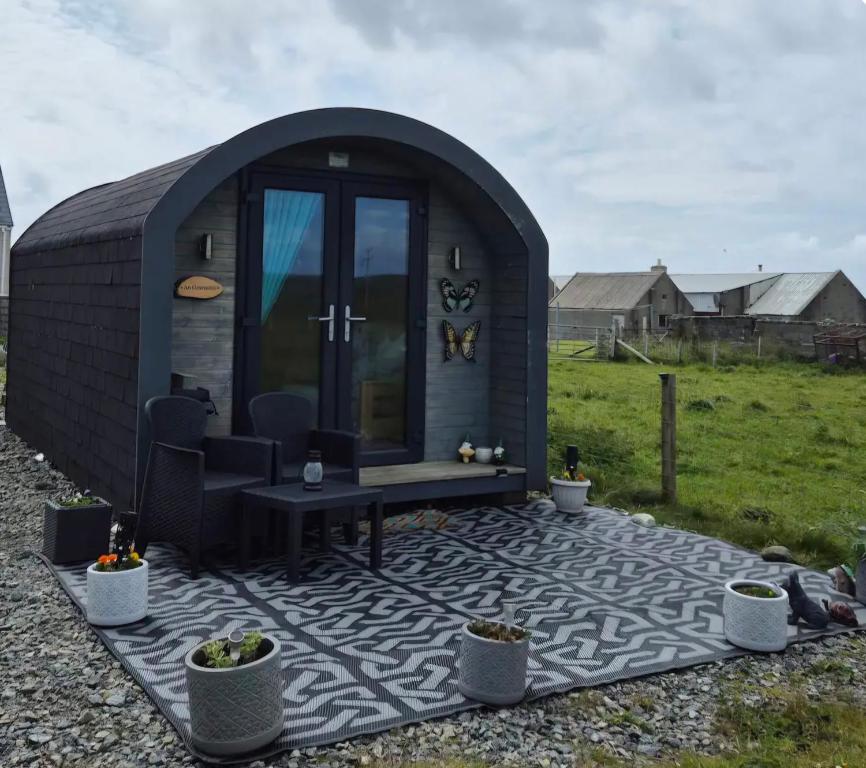a small black shed with a chair and a table at An Gearasdan in Eoropie