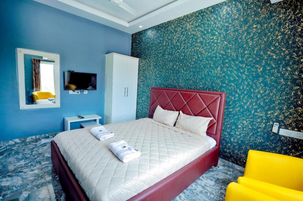 a bedroom with a large bed with blue walls at Hotel Rieejh in Nāgercoil