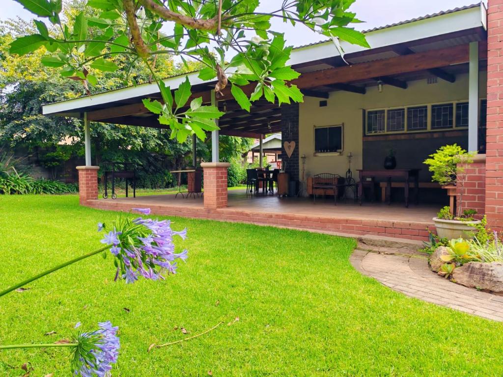 a house with a green yard with purple flowers at Zu Hause in Piet Retief
