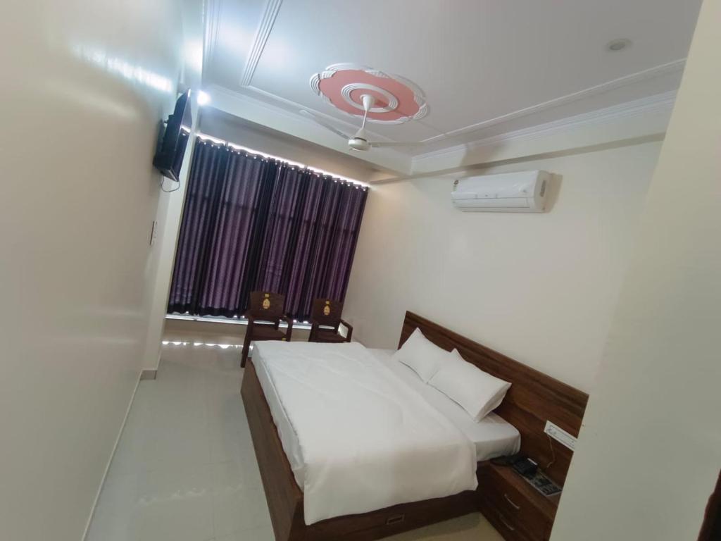 ein Schlafzimmer mit einem weißen Bett und einem Fenster in der Unterkunft Hotel GR Palace in Sheodāspura
