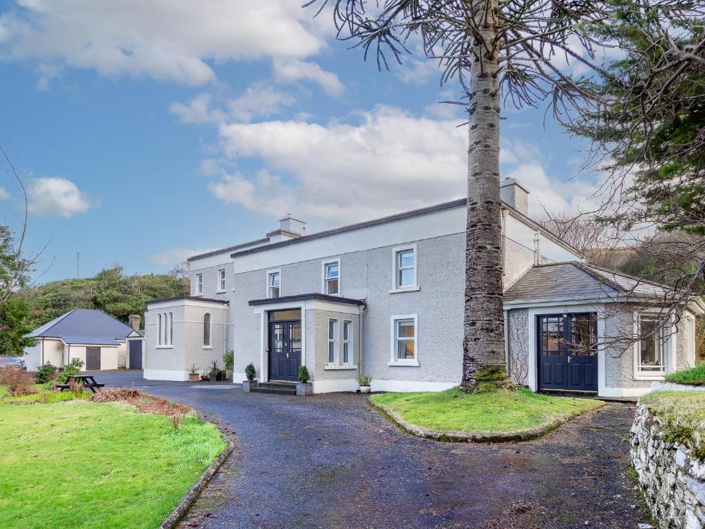an exterior view of a white house with a tree at The Convent Leenane in Leenaun