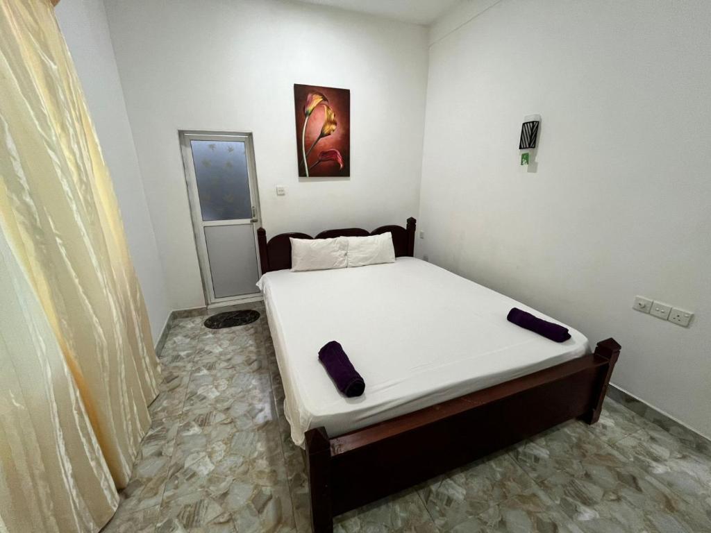 a small bedroom with a bed with white sheets at BeachBay Guest House in Negombo