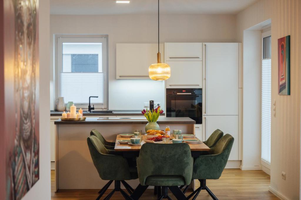 a kitchen with a table and green chairs in a room at Penthouse `Wolke 7` am See mit Sauna in Lembruch