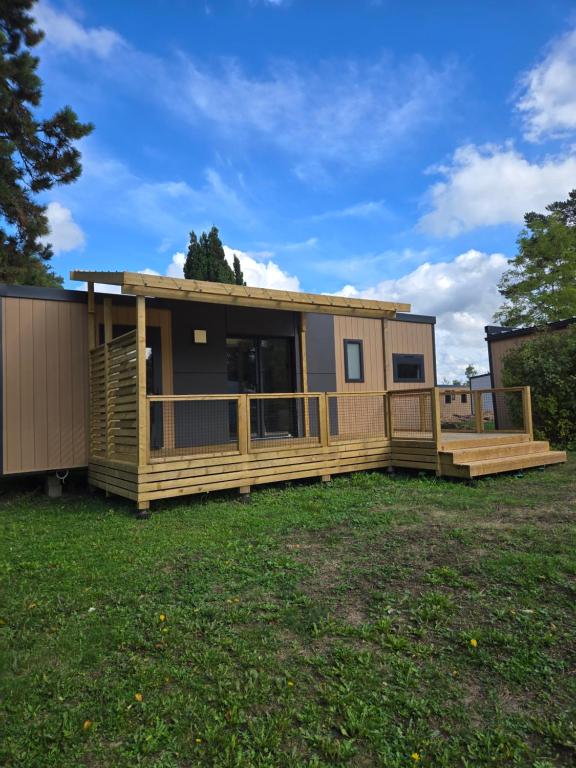 a modular home with a deck on a yard at Mobil-home Harmonie in Gouvieux