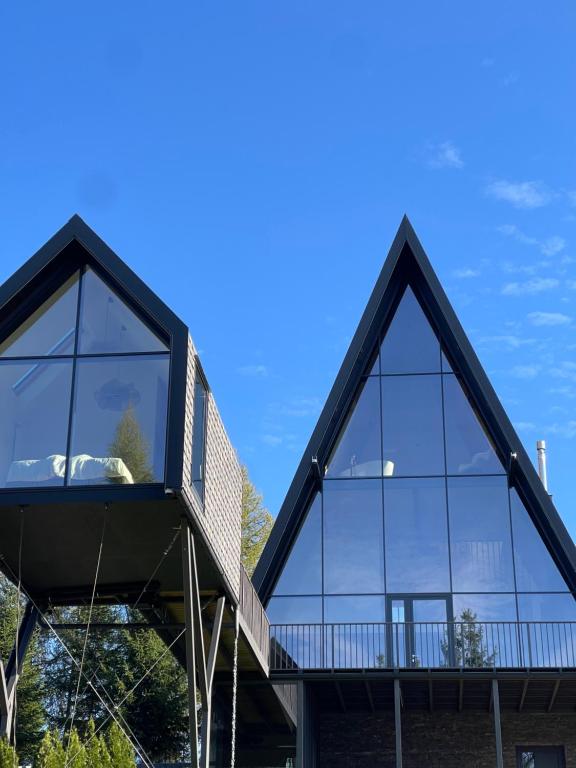 a house with large glass windows on the side of it at TwoTop-Premium Chalet Villa with mountain view in Piatra Fantanele