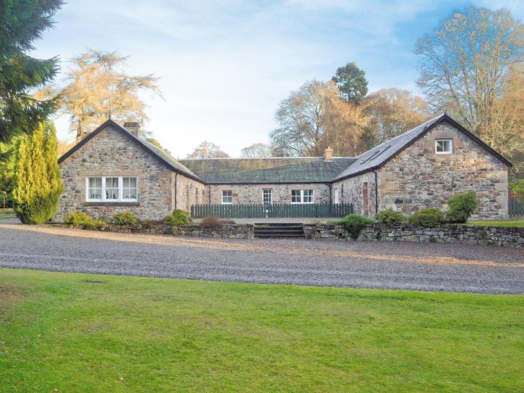 a large stone house with a stone wall at Ladybird Cottage in Lochend