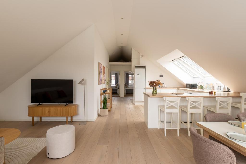 a white living room with a kitchen and a living room at Sunlit Loft Apartment in Valby with Parking for 8 in Copenhagen