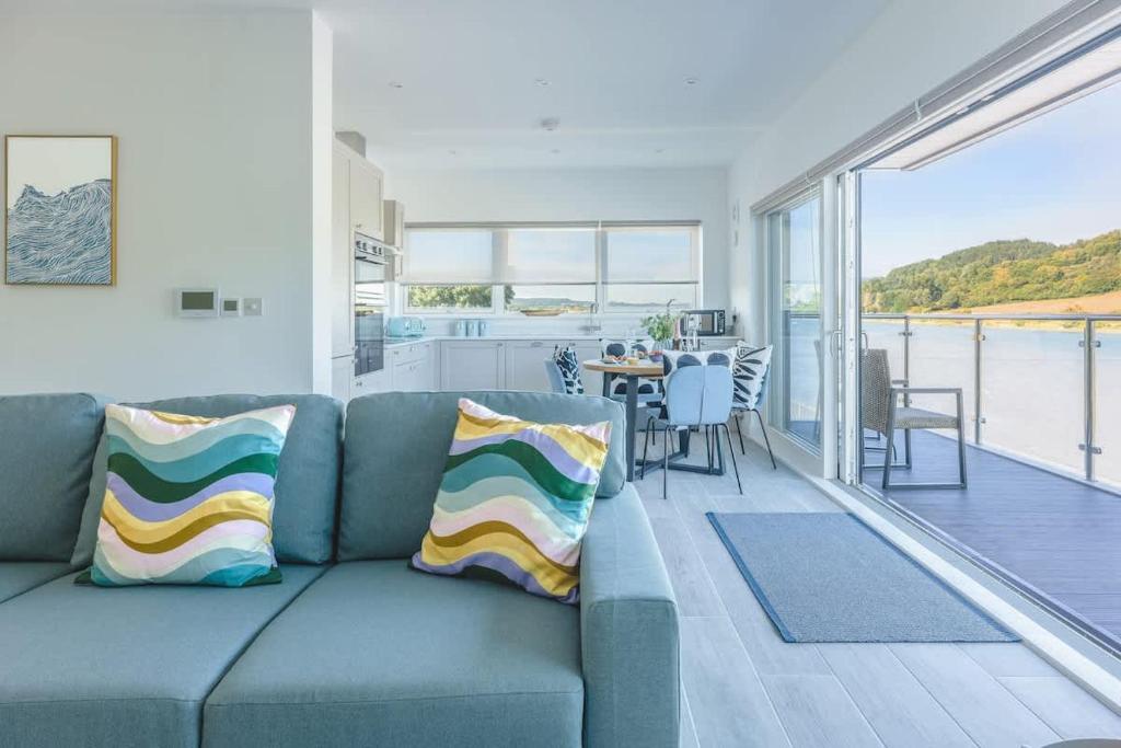 a living room with a blue couch and a balcony at River View - Prime River Front Location in Seaton