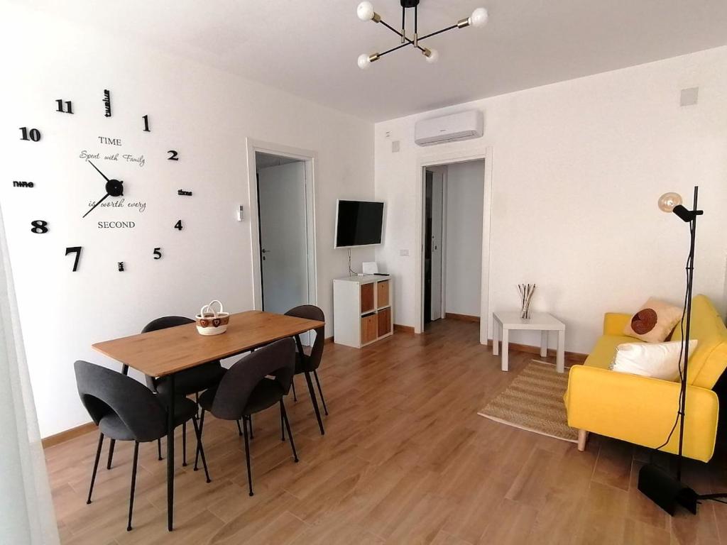 a living room with a table and a clock on the wall at La Dimora del Cuore - U1598 in Olbia