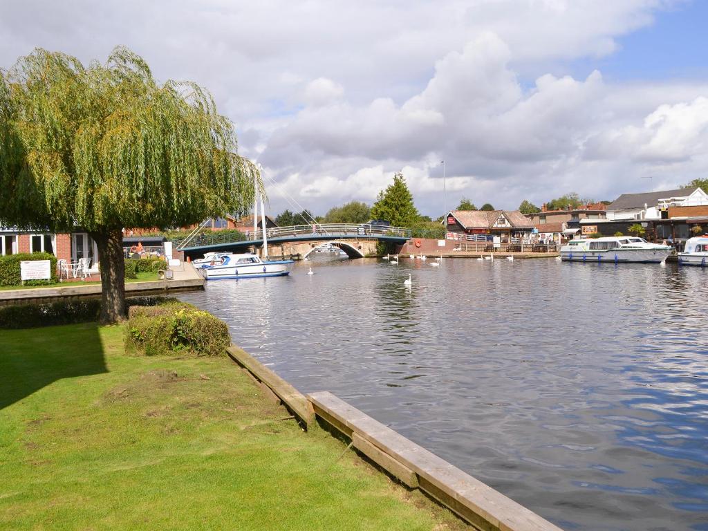 a river with boats on it with a bridge at Puffin Cottage in Wroxham