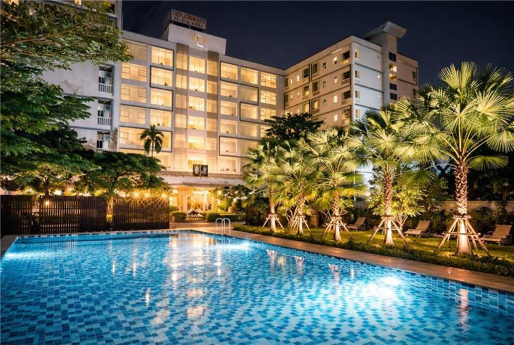 a swimming pool in front of a hotel at night at Sunday Platinum Suites in Bangkok