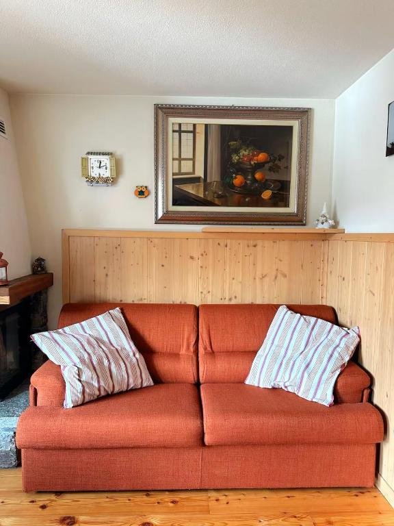 an orange couch in a living room with a mirror at Chalet del Borgo in Le Bratte