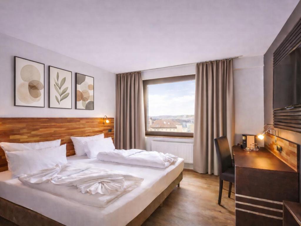 a hotel room with a bed and a desk and a window at Luna Inn Stuttgart City in Stuttgart