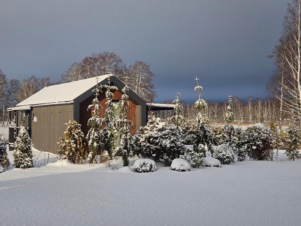 a small church with snow covered bushes and a cross at Berzkrasti Lake House with Private Sauna & Beach in Sigulda