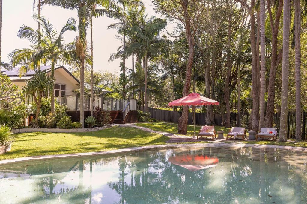 a swimming pool with a red umbrella and two chairs at Sunrise Guesthouse in Byron Bay
