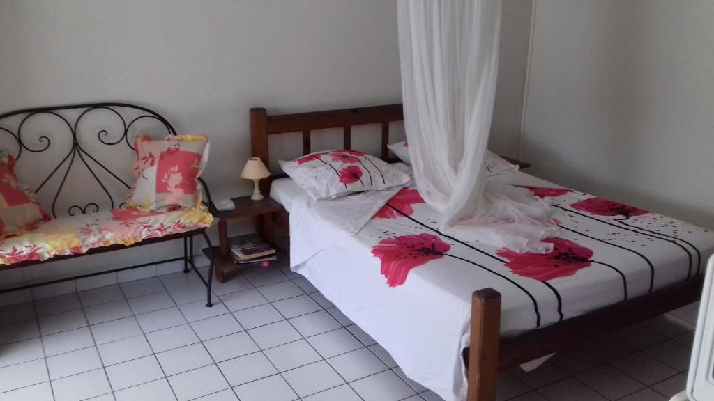 Dos camas en una habitación con flores rojas. en Meridienne Creole, en Sainte-Anne