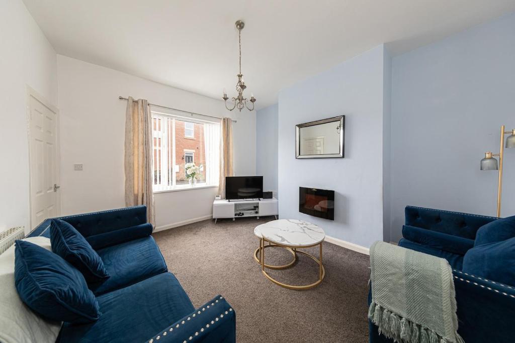 a living room with two blue couches and a tv at The Cosy Durham Nest in Langley Park