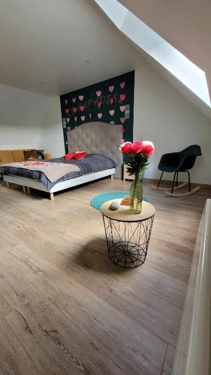 a bedroom with a bed and a table with flowers at " Bulles et Evasion - Maison, Spa en option" in Ville-le-Marclet