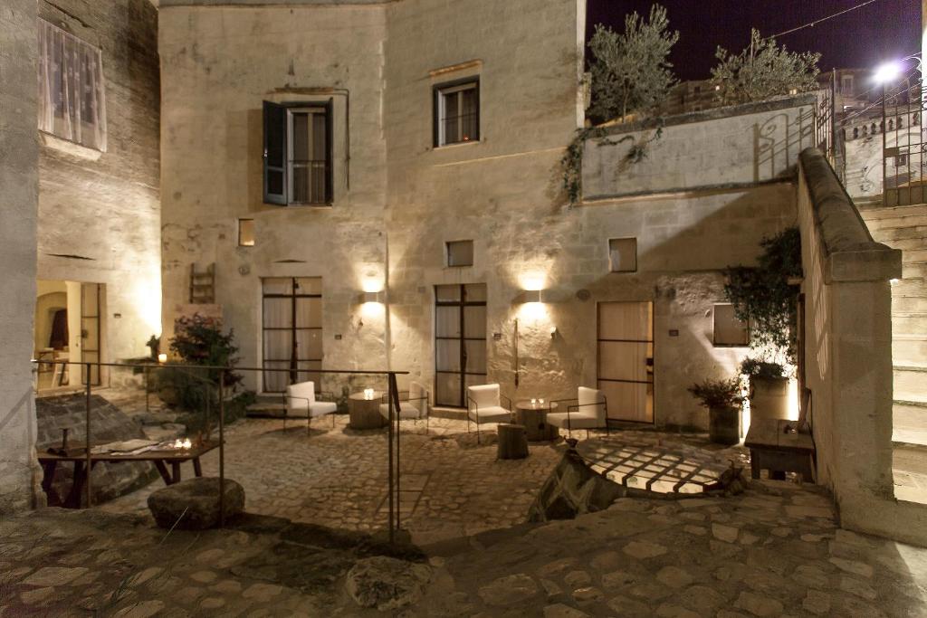 a large stone building with a courtyard at night at Corte San Pietro in Matera