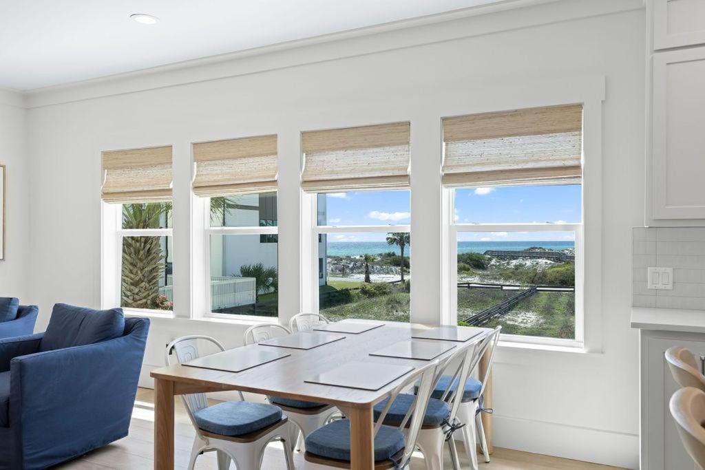 a dining room with a table and chairs and windows at 26 Blue Coast Ct in Inlet Beach