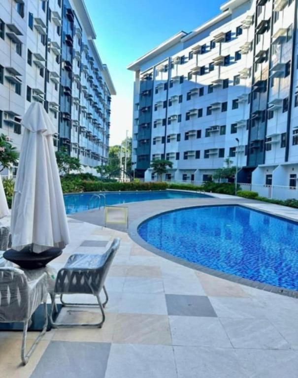 a pool with a chair and an umbrella next to a building at R and K staycation in Manila