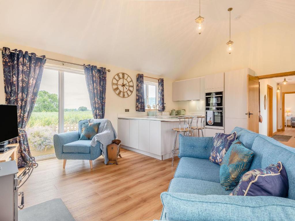 a living room with a blue couch and a kitchen at Violet Cottage in Hereford