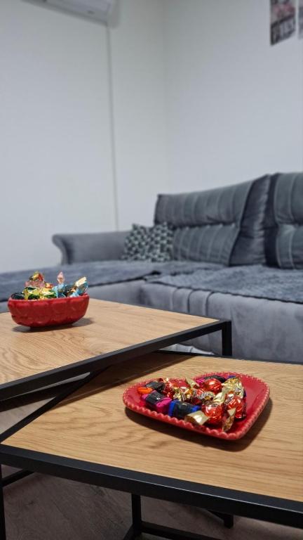 two tables in a living room with a plate of candy at Apartman AURORA Trstenik in Trstenik