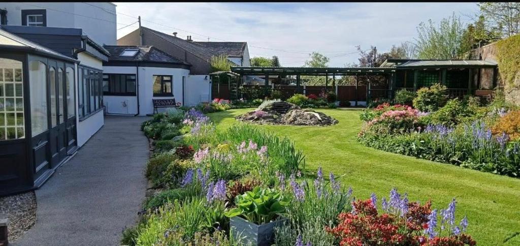 a garden with flowers and plants in front of a building at Three Trees Cottage in Lochmaben
