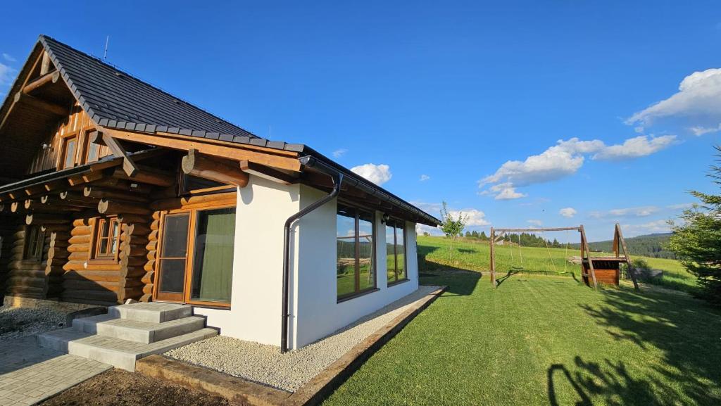 a small wooden house with a grass yard at Zrubová chata Jakub in Oravská Lesná