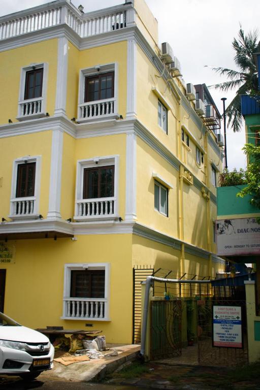 a yellow and white building with a car parked in front at Hotel Soft Petal BB Block in Kolkata