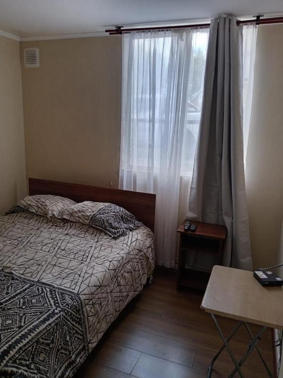 a bedroom with a bed and a window and a table at departamento Eli in Valdivia