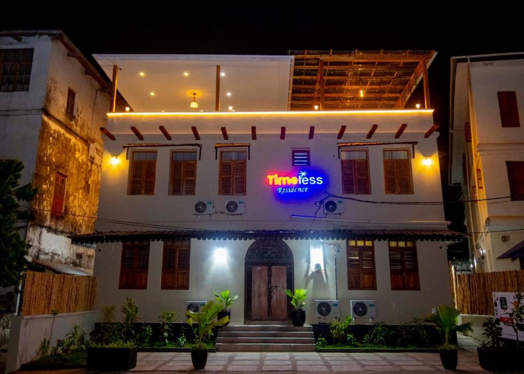 a white house with a neon sign on it at night at Timeless Residency in Zanzibar City