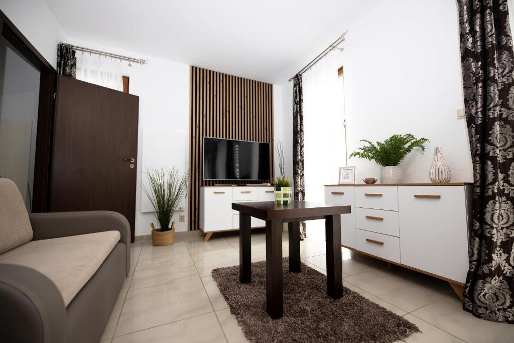a living room with a couch and a table and a tv at Apartament IKAR blisko morza in Rewal