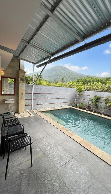 a swimming pool on a patio with two benches next to it at Amerthya Villa in Banjar