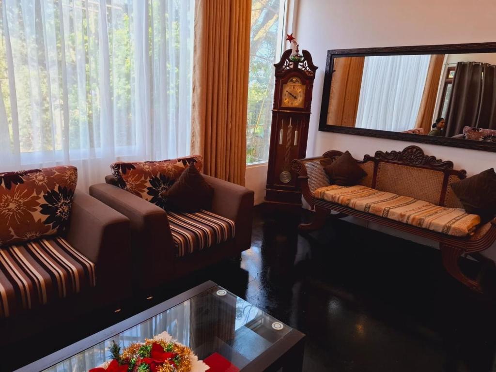 a living room with two couches and a clock at Rock House Villa in Kandy